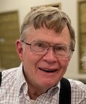 A man with glasses smiles for a closeup.