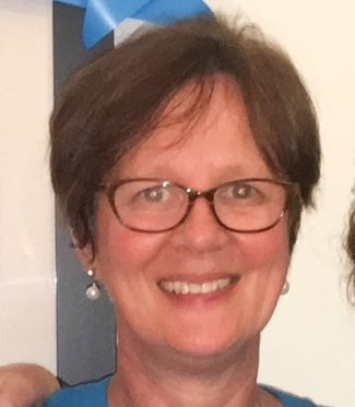 A woman with glasses smiles.