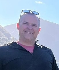 A man stands in front of a mountain.