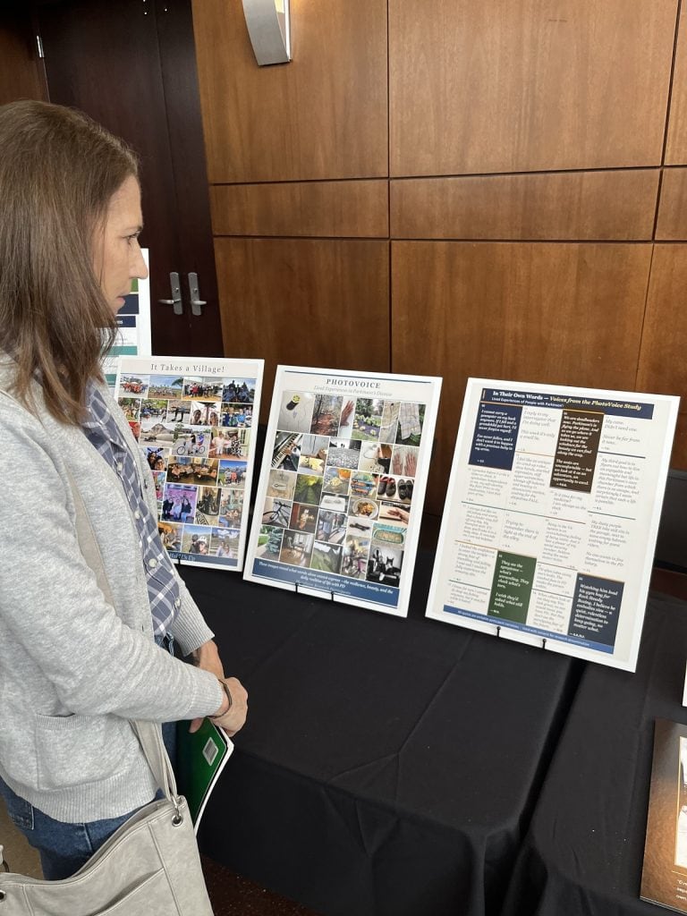 A woman looks intently at a row of small posters on a table.