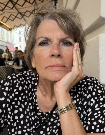 A woman looks serious while leaning on her arm on a table.